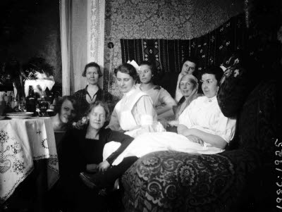 Interiör; gruppbild åtta damer (två sjuksköterskor). Oidentifierade.