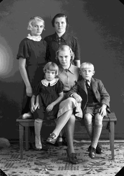 Porträtt av en dam och fyra barn; pojke, flickor. Ateljefoto.