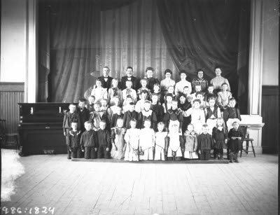 Godtemplarhuset, interiör; gruppbild: Godtemplare. Vuxna och barn framför scenen. Oidentifierade.