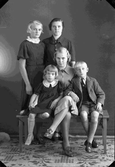 Porträtt av en dam och fyra barn; pojke, flickor. Ateljefoto.