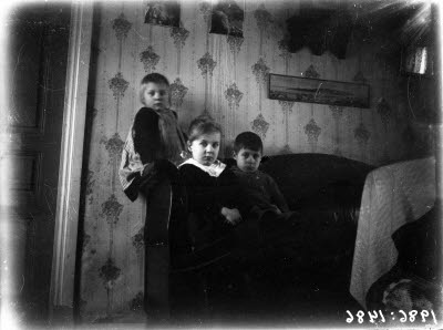 Två pojkar och en flicka. Hemmiljö; vardagsrum.