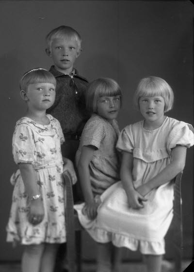 Porträtt av fyra barn; en pojke och tre flickor. Ateljefoto.