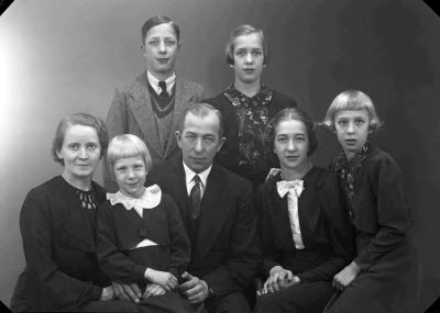 Porträtt av en herre och en dam med fem barn; flickor, pojke. Ateljefoto.