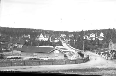 Vägen till bolagsområdet med järnvägsbron. I bakgrunden Johannes. Disponentvillan och Bolagskontoret , LKAB kontor. Sommarmotiv.