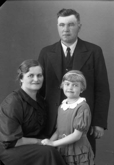 Porträtt av en herre, en dam och ett barn; flicka. Ateljefoto.