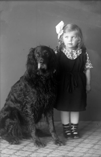 Porträtt av ett barn, flicka med hund. Ateljefoto.