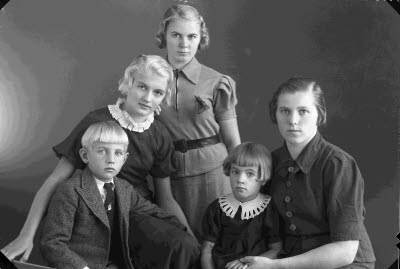 Porträtt av en dam och fyra barn; pojke, flickor. Ateljefoto.