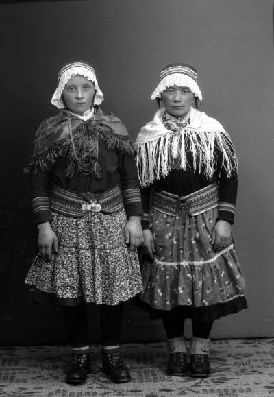 Porträtt av två damer i samedräkter. Ateljefoto.