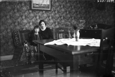 En kvinna och ett barn med en katt. Hemmiljö; vardagsrum.