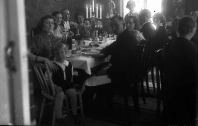 Interiör vardagsrum; festdeltagare runt dukat bord. Oidentifierade.