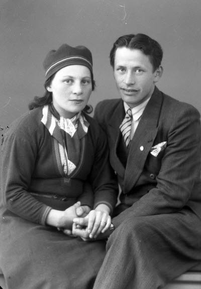 Porträtt av ett par; dam i samedräkt. Ateljefoto.