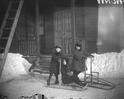 Tre barn med sparkslädar.