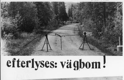 Provisorisk vägbom; kedja, stativ. Skylt: "In- och utfart". Skogsbilväg.