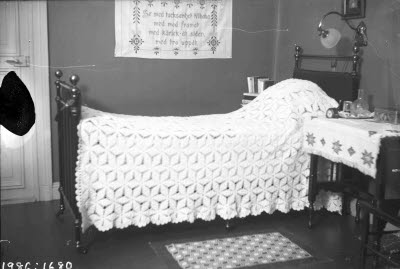 Fransk järnsäng med virkat överkast.