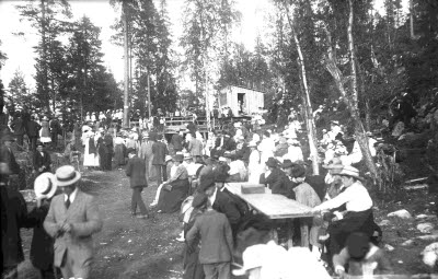 Naturbild: tillställning; stor folksamling vid friluftsscen eller dansbana. Oidentifierade.
