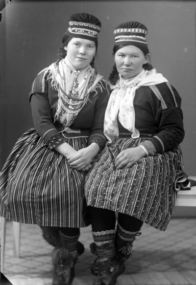 Porträtt av två damer i samedräkter. Ateljefoto.