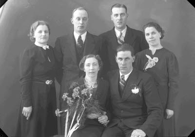 Porträtt av ett brudpar samt två herrar och två damer. Ateljefoto.