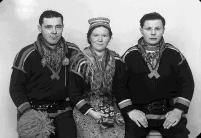 Porträtt av två herrar och en dam i samedräkter. Ateljefoto.