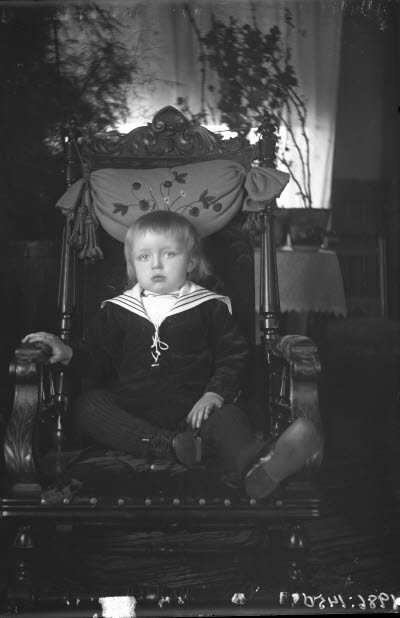 Ett barn. Pojke i hemmiljö. Vardagsrum. Länsstol.