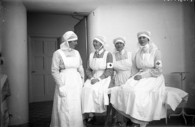 Fyra sjuksköterskor, operationssköterskor. Sjukvårdsmiljö; behandlingsrum.