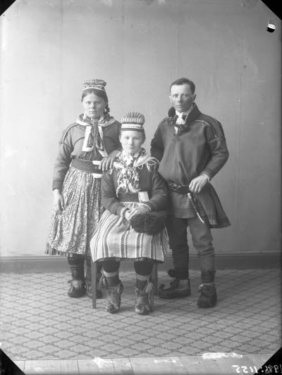 Porträtt av 2 damer och en herre i samedräkter. Ateljefoto.