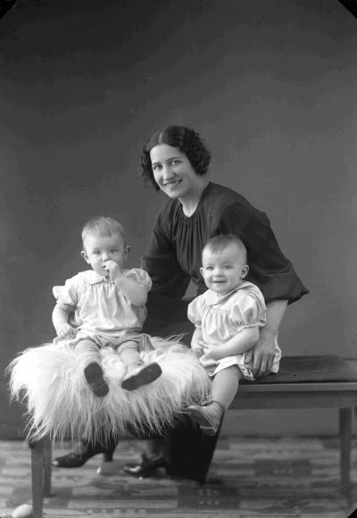 Porträtt av en dam och två barn. Ateljefoto.