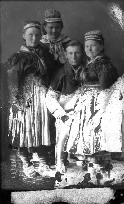 Porträtt av en herre och tre damer i samedräkter. Ateljefoto.