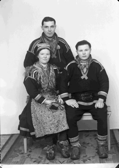 Porträtt av två herrar och en dam i samedräkter. Ateljefoto.