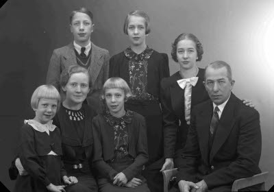 Porträtt av en herre och en dam med fem barn; flickor, pojke. Ateljefoto.