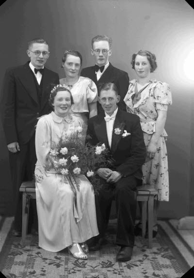 Porträtt av ett brudpar samt två herrar och två damer. Ateljefoto.