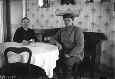 En äldre herre och dam. Hemmiljö; vardagsrum. Soffa.