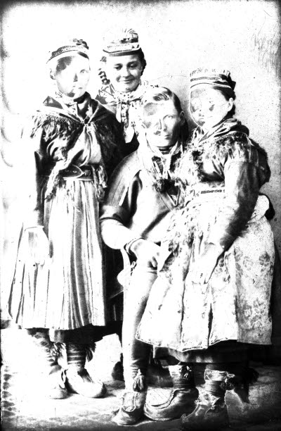 Porträtt av en herre och tre damer i samedräkter. Ateljefoto.