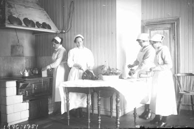 Gruppbild: matlagning; kokerskor i arbete. Interiör: kök. Möjligen sjukhuset eller Kaptensgårdens sanatorium. Oidentifierade.